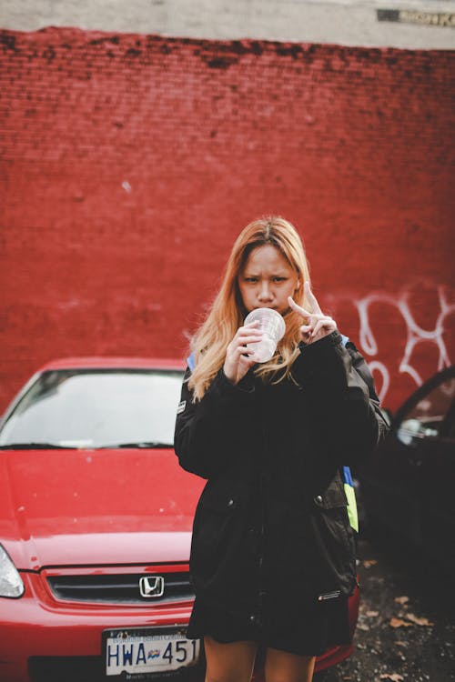 Woman Holding Plastic Cup Beside Red Honda Vehicle