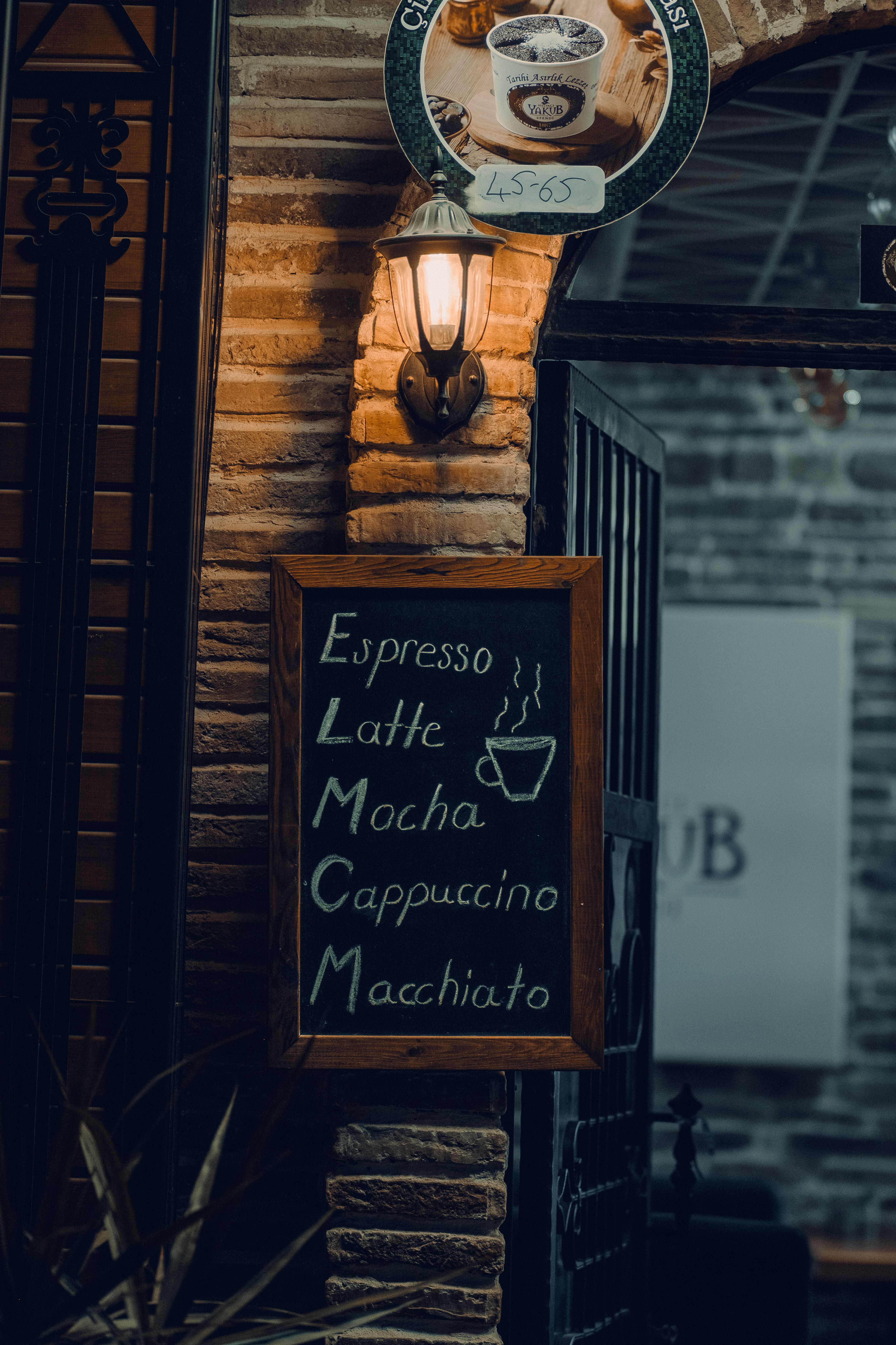 Chalkboard menu displaying coffee options at a cozy café with warm ambient lighting.
