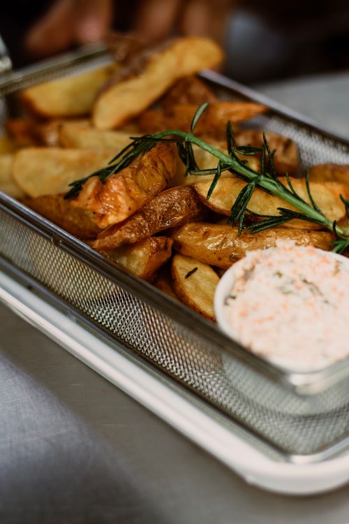 Free Crispy potato wedges served with a flavorful dip, garnished with fresh rosemary. Stock Photo