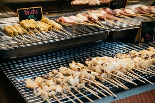 Close-up of skewered street food items in a Bangkok market stall.