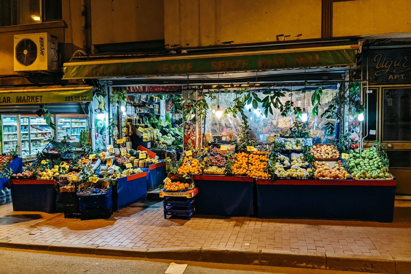 An illuminated stall of fruit and vegetables in the evening
