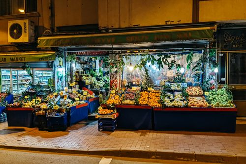 Free A bustling night market stall offering a colorful array of fresh fruits and vegetables on the city sidewalk. Stock Photo