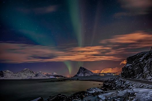Stunning view of the aurora borealis illuminating a snowy mountain landscape at night.