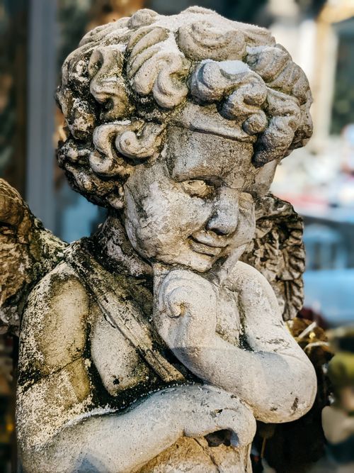 Free Close-up of an eroded stone angel statue with intricate details and a contemplative expression. Stock Photo