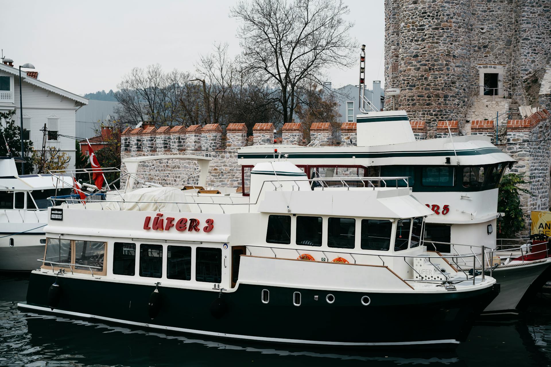 Ferries moored by the historic Anadoluhisarı fortress in Istanbul, showcasing Ottoman architecture.