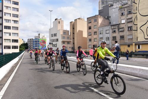 Free A group of cyclists enjoying a leisurely ride through a bustling urban street with colorful murals. Stock Photo