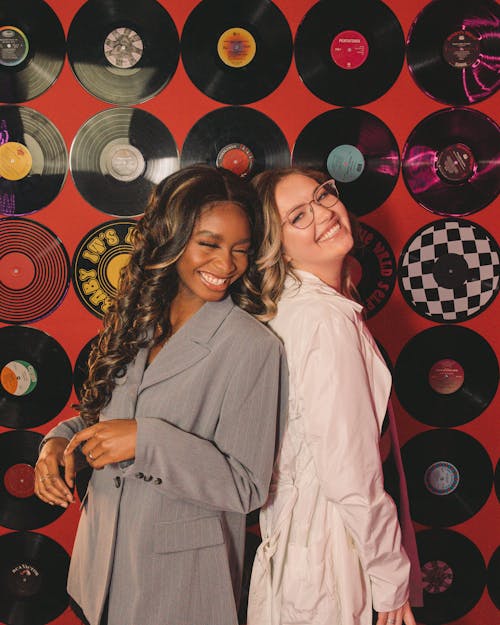 Two Young Women Standing Back to Back and Smiling