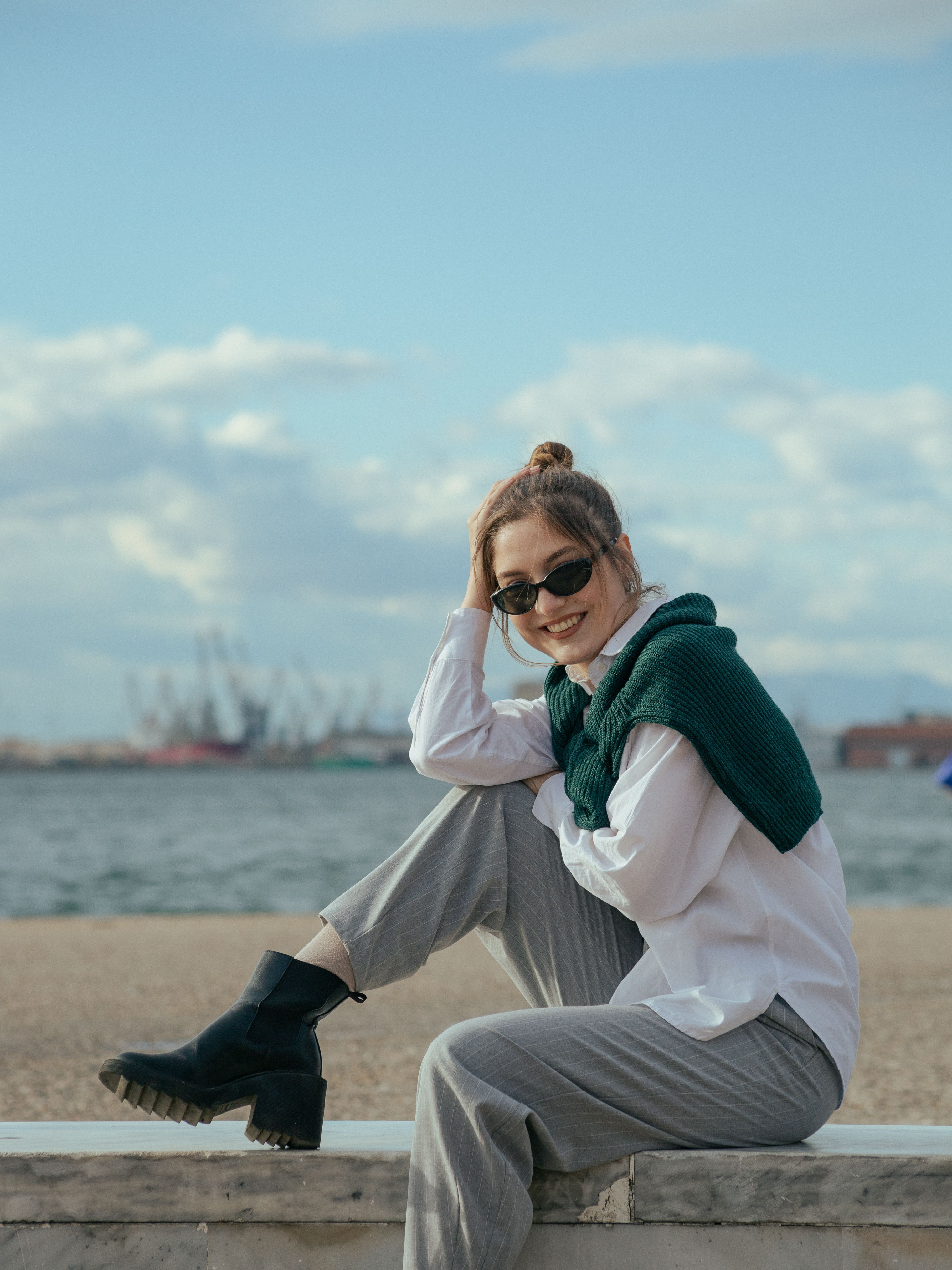 Young Woman Sitting on a Wall on the Seashore and Smiling · Free Stock ...