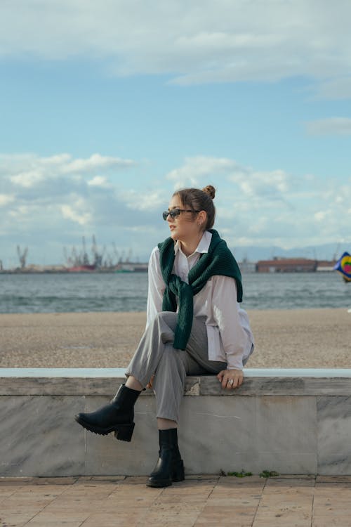 Young Woman Sitting on a Wall on the Seashore 