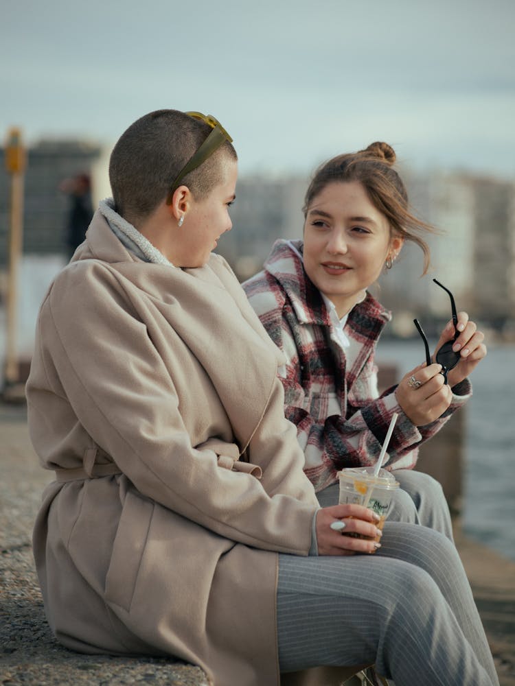 Young Women Sitting On The Beach And Talking 