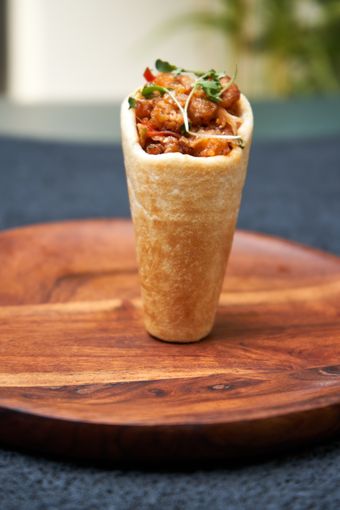 Savoury filled bread cone on a round wooden board, photo by dhiraj jain on Pexels