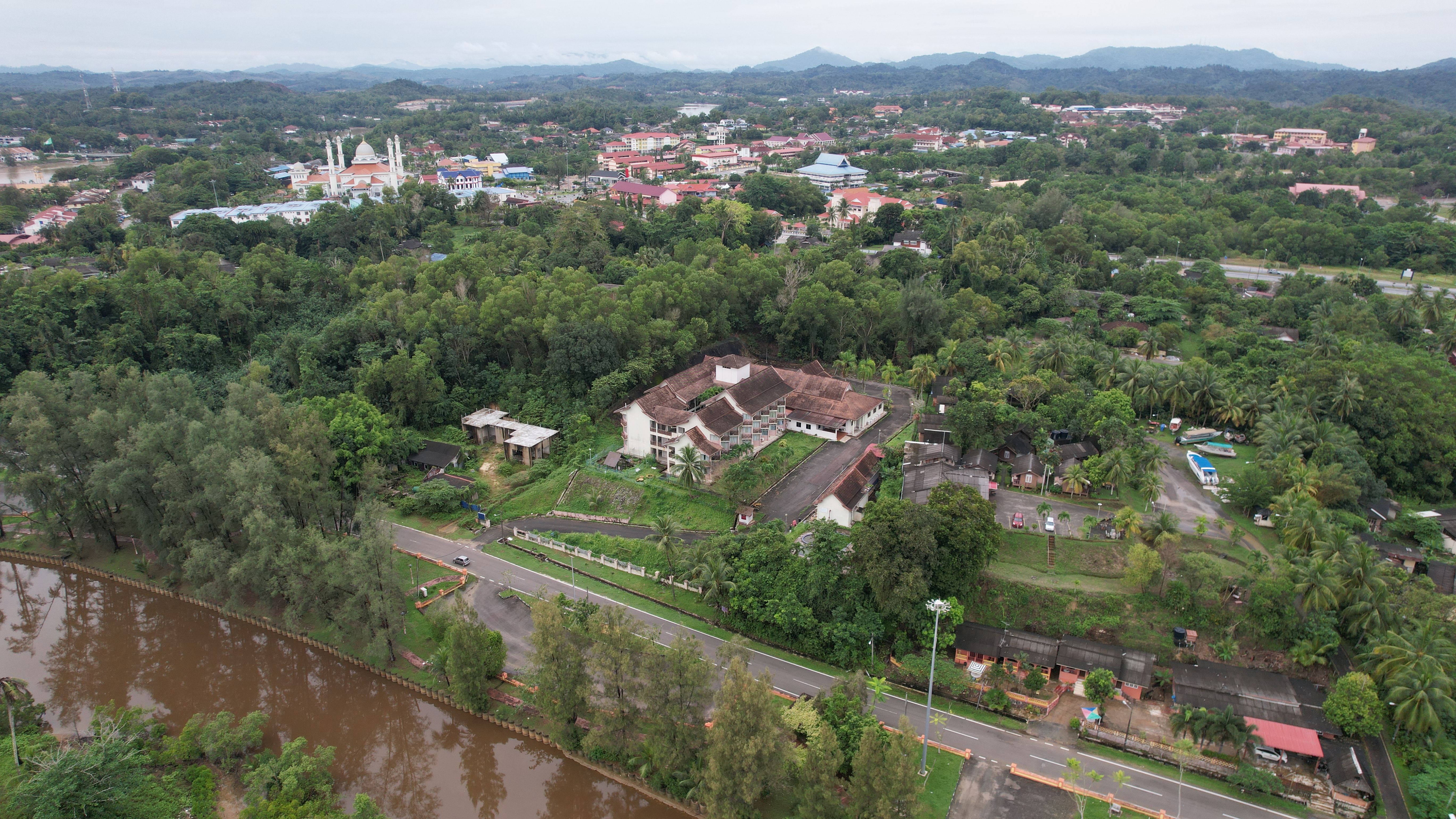 Explore an aerial view of Marang, Malaysia, showcasing lush greenery, buildings, and a river.