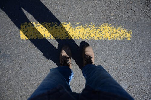 A person standing on a yellow line with their feet