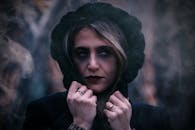 户外，一个穿着黑色兜帽的女人，表情喜怒无常的特写肖像