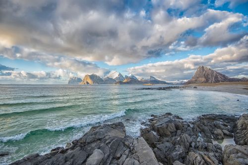 Free Breathtaking seascape with rocky shoreline and majestic Norwegian mountains under dramatic clouds. Stock Photo