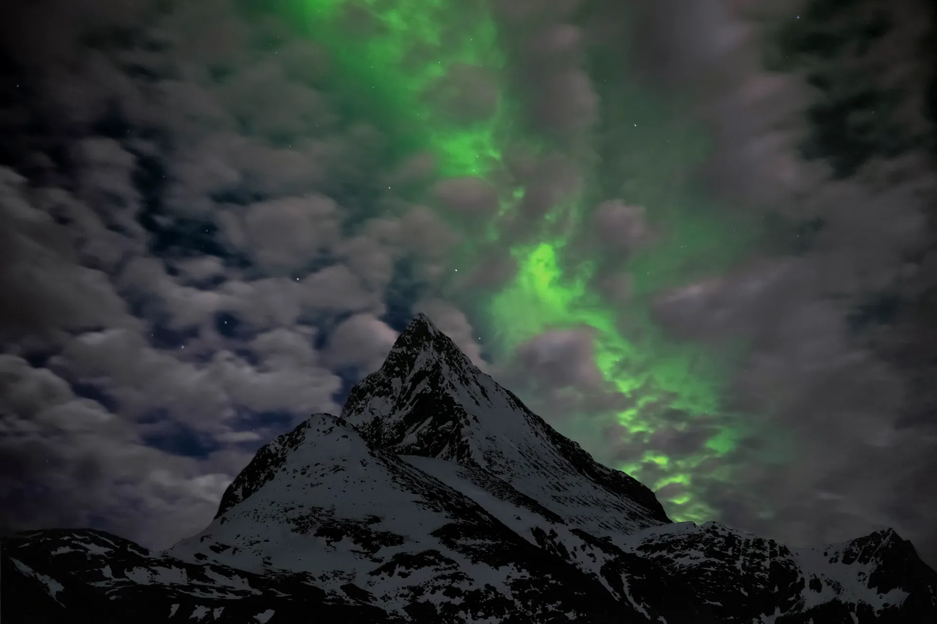 Green aurora glow low on the northern horizon above a dark valley Green aurora glow low on the northern horizon above a dark valley