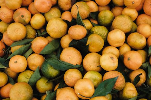 Free A vibrant pile of fresh tangerines with green leaves, showcasing texture and color. Stock Photo