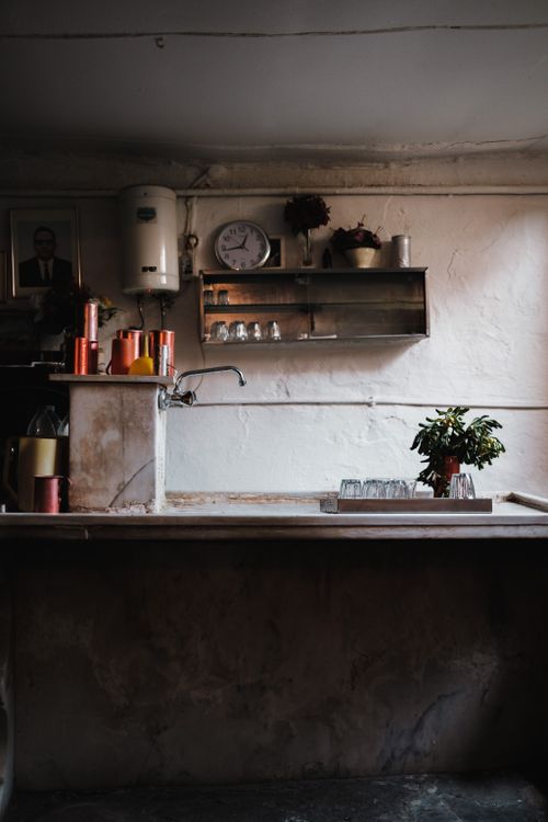 Free Cozy kitchen scene with rustic decor, a wall clock, and potted plants on a wooden worktop. Stock Photo