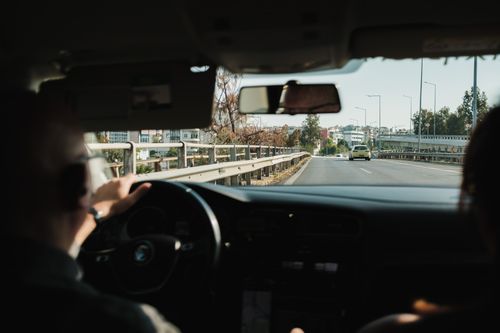 Free Interior view of a car driving through a city with the road ahead clear and buildings visible. Stock Photo