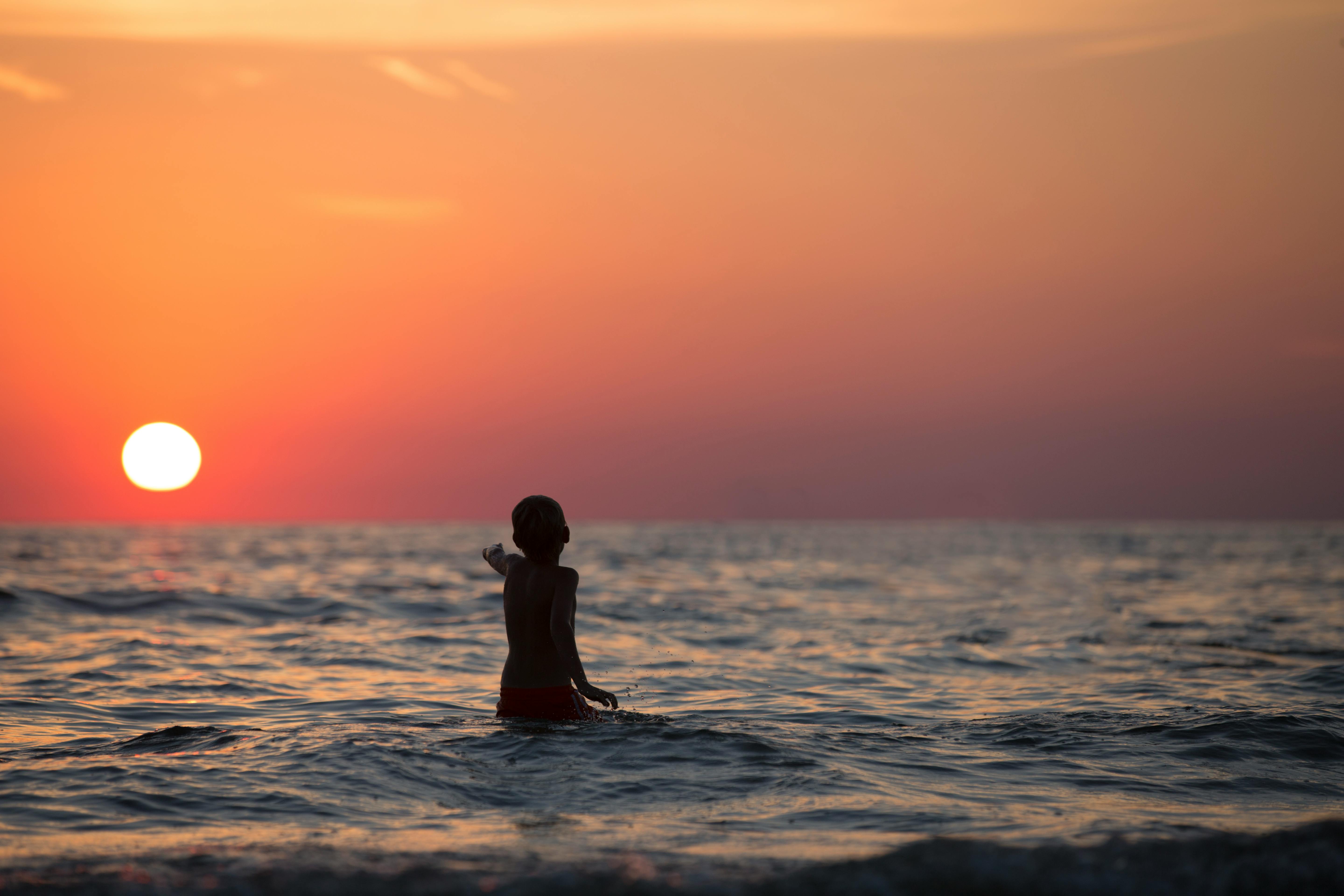 boy in ocean during golden hour