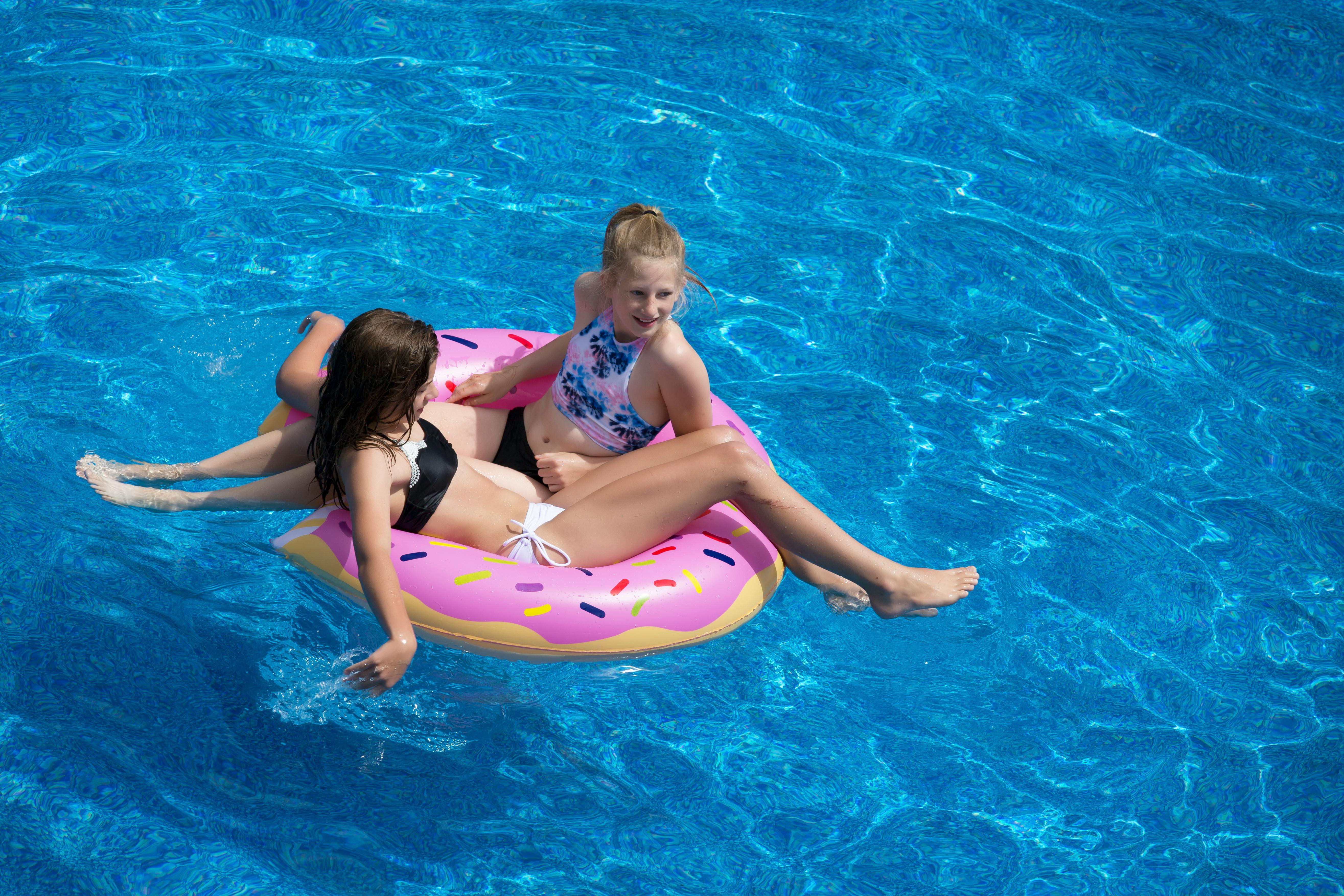 Two girls sitting on a pool float. | Photo: Pexels