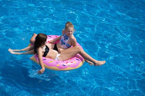 Deux Filles Assises Sur Un Flotteur De Piscine Donut Rose