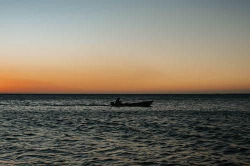 Free A serene scene of a man in a boat on the sea during a beautiful sunset in Santa Marta, Colombia. Stock Photo