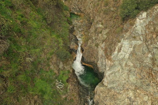 A dramatic aerial view of a waterfall cascading through a rocky gorge in Málaga, Spain.
