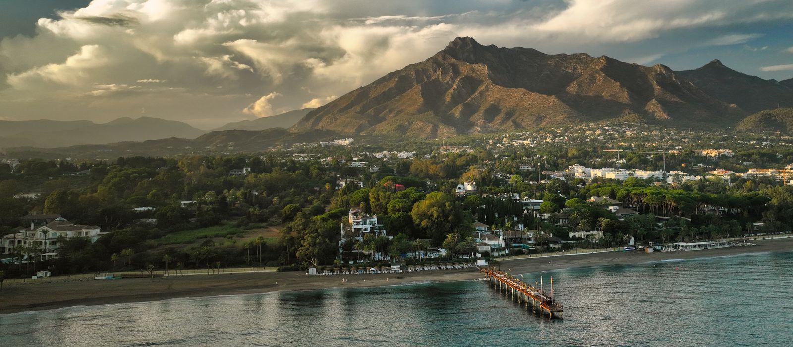 A breathtaking aerial view of Marbella's coastline, lush greenery, and majestic mountains.