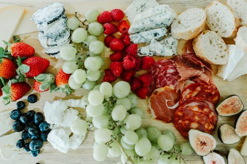 Free A vibrant charcuterie board featuring assorted cheeses, meats, and fresh fruits on a wooden surface. Stock Photo
