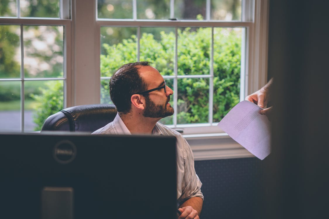 Free Man Sitting in Black Leather Chair Near Window Stock Photo