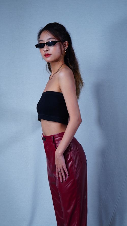 Free Fashionable woman posing in a studio, wearing black top and red leather pants. Stock Photo