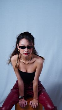 Stylish woman posing in chic outfit with bold sunglasses indoors.