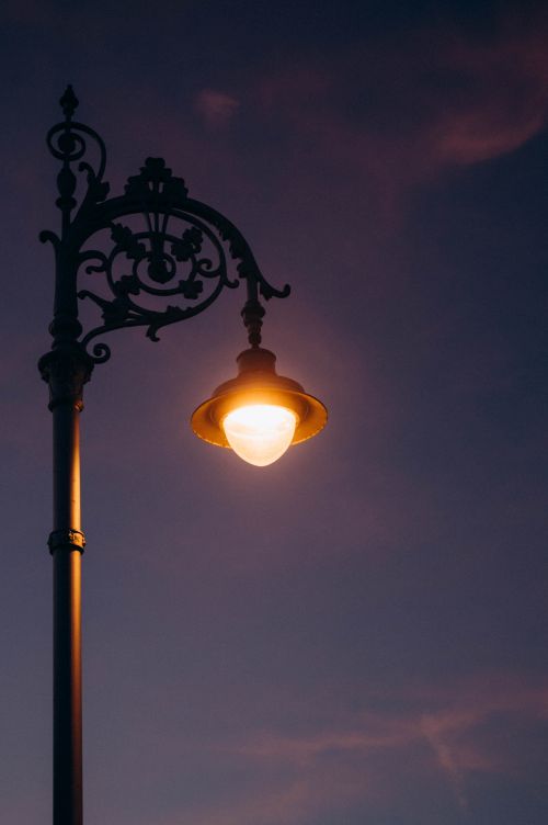 Free A vintage iron street lamp gleams warmly against a deep twilight sky, evoking urban nostalgia. Stock Photo