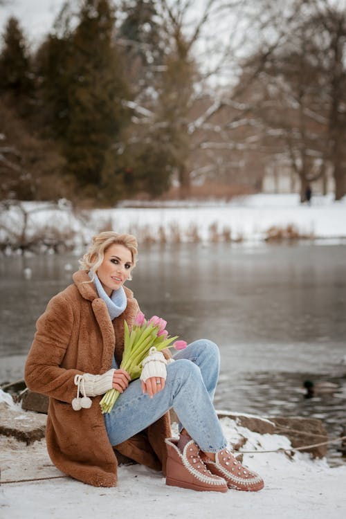 Smiling Woman Holding Flowers at Winter Lake