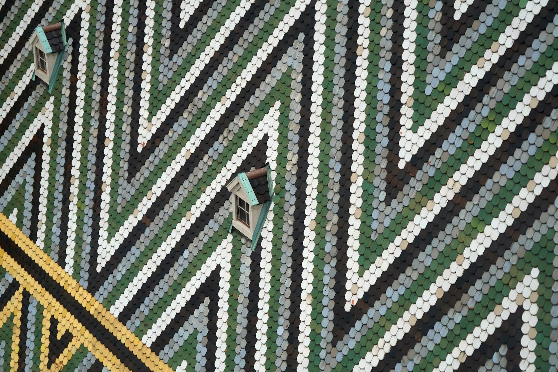 Close-up of a geometric pattern tile roof featuring two dormer windows.