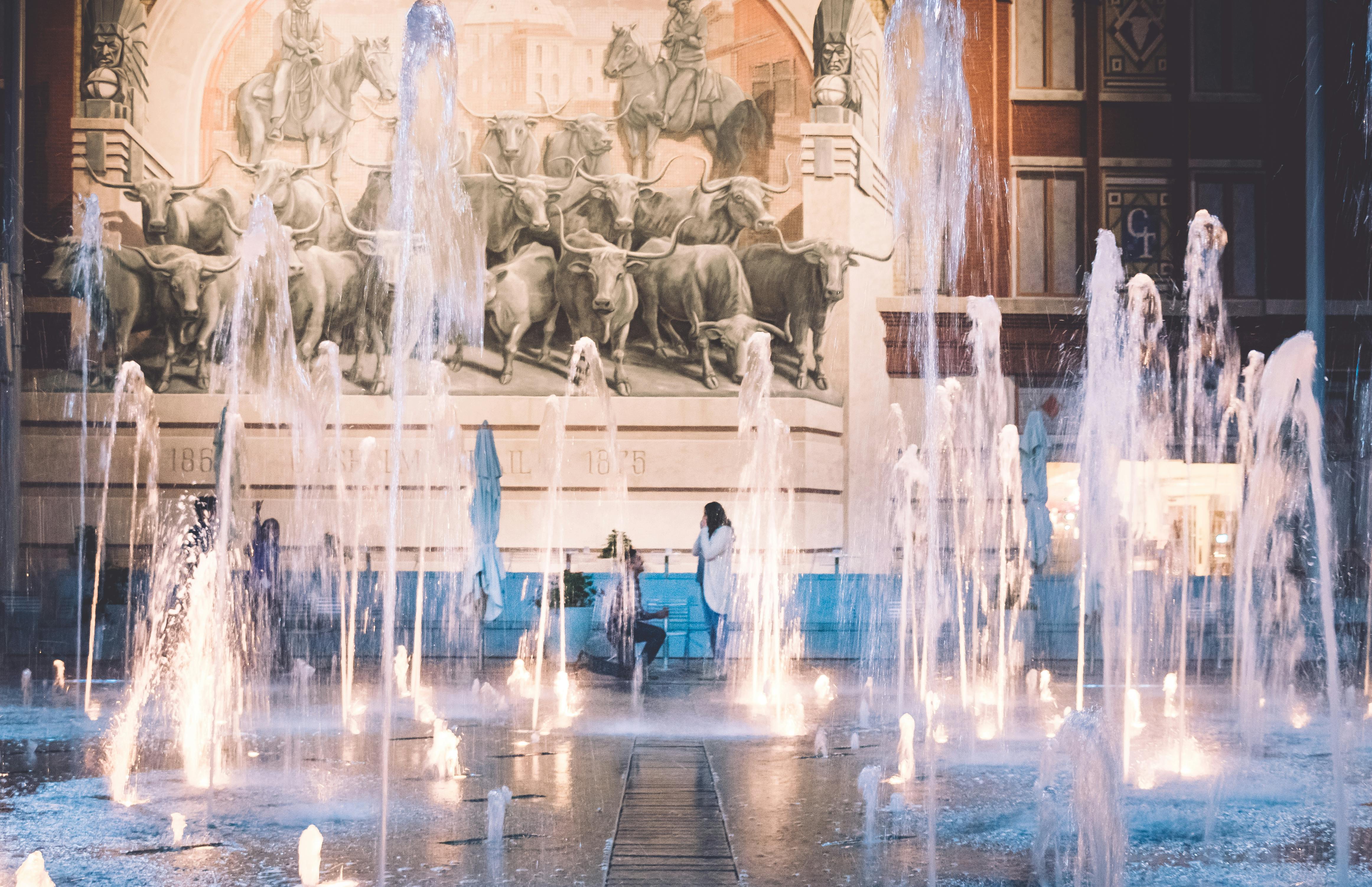 man proposing to woman on water fountain display