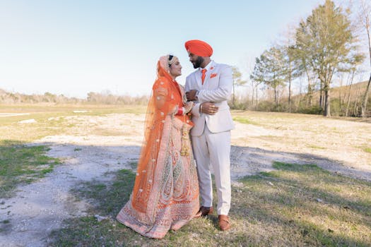A couple in vibrant traditional Indian attire embracing outdoors under a clear sky.