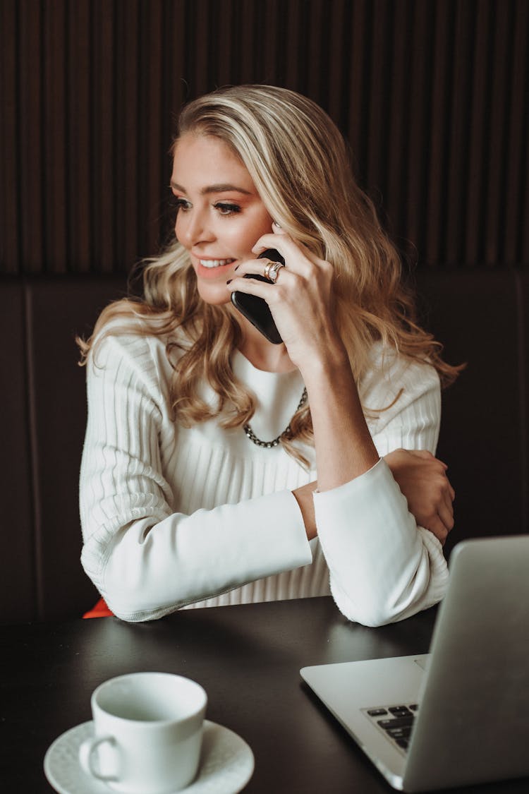 Portrait Of Woman Answering Phone Call Sitting By Desk