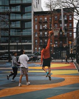 Men playing basketball on an outdoor court in New York City, showcasing urban sports culture.