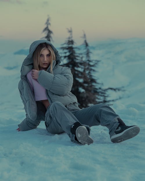 Blonde Model in Jacket Sitting on Snow