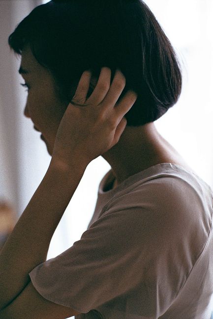A silhouette of a woman with short hair and a t-shirt, touching her hair thoughtfully.