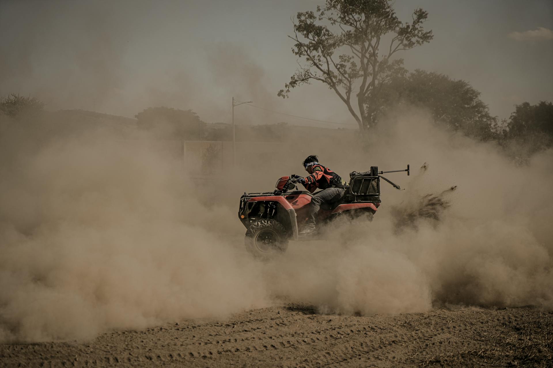 Man riding a quad bike through dusty off-road terrain, showcasing adventure and thrill.