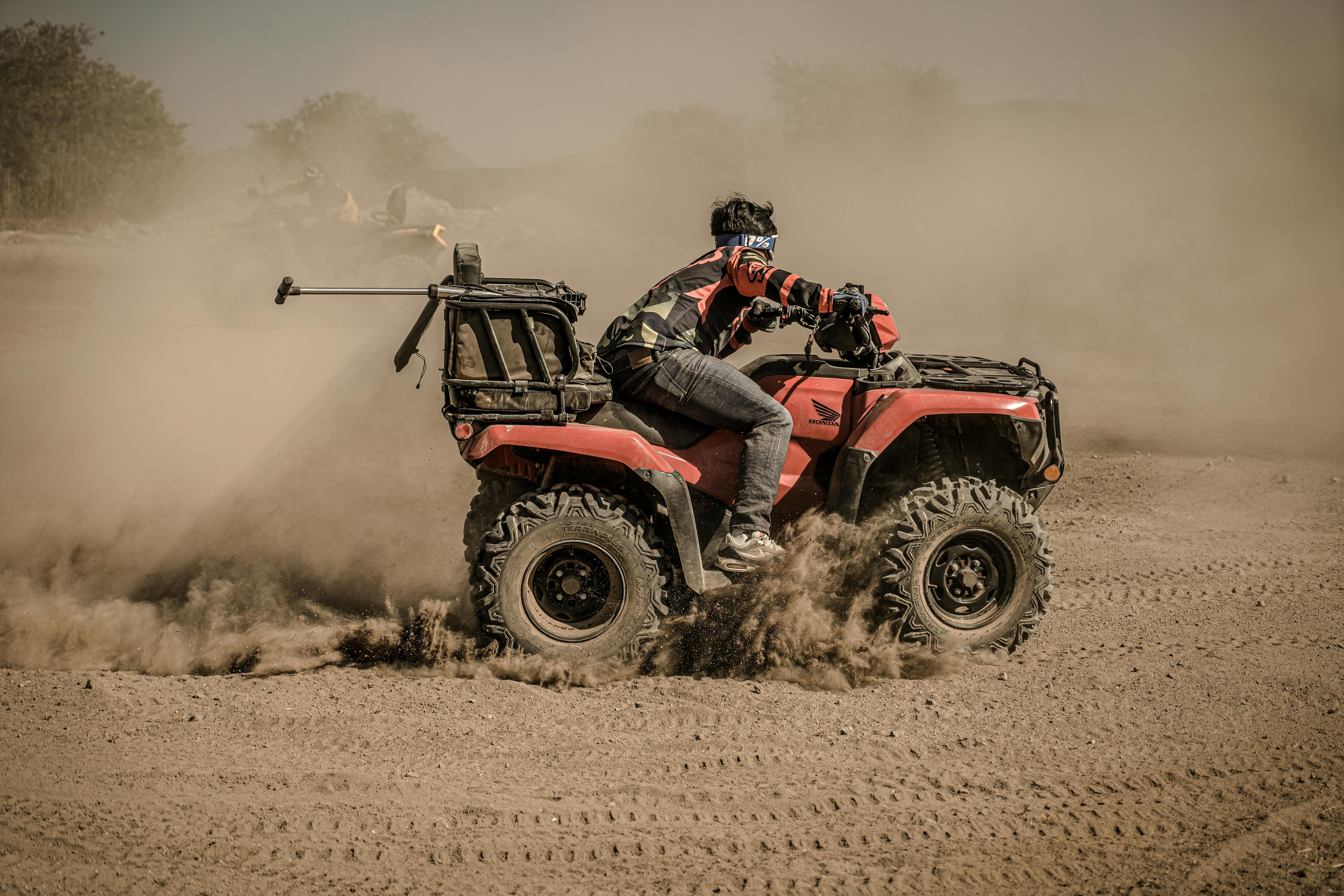 A man riding an ATV through dusty terrain, showcasing off-road adventure and sport.