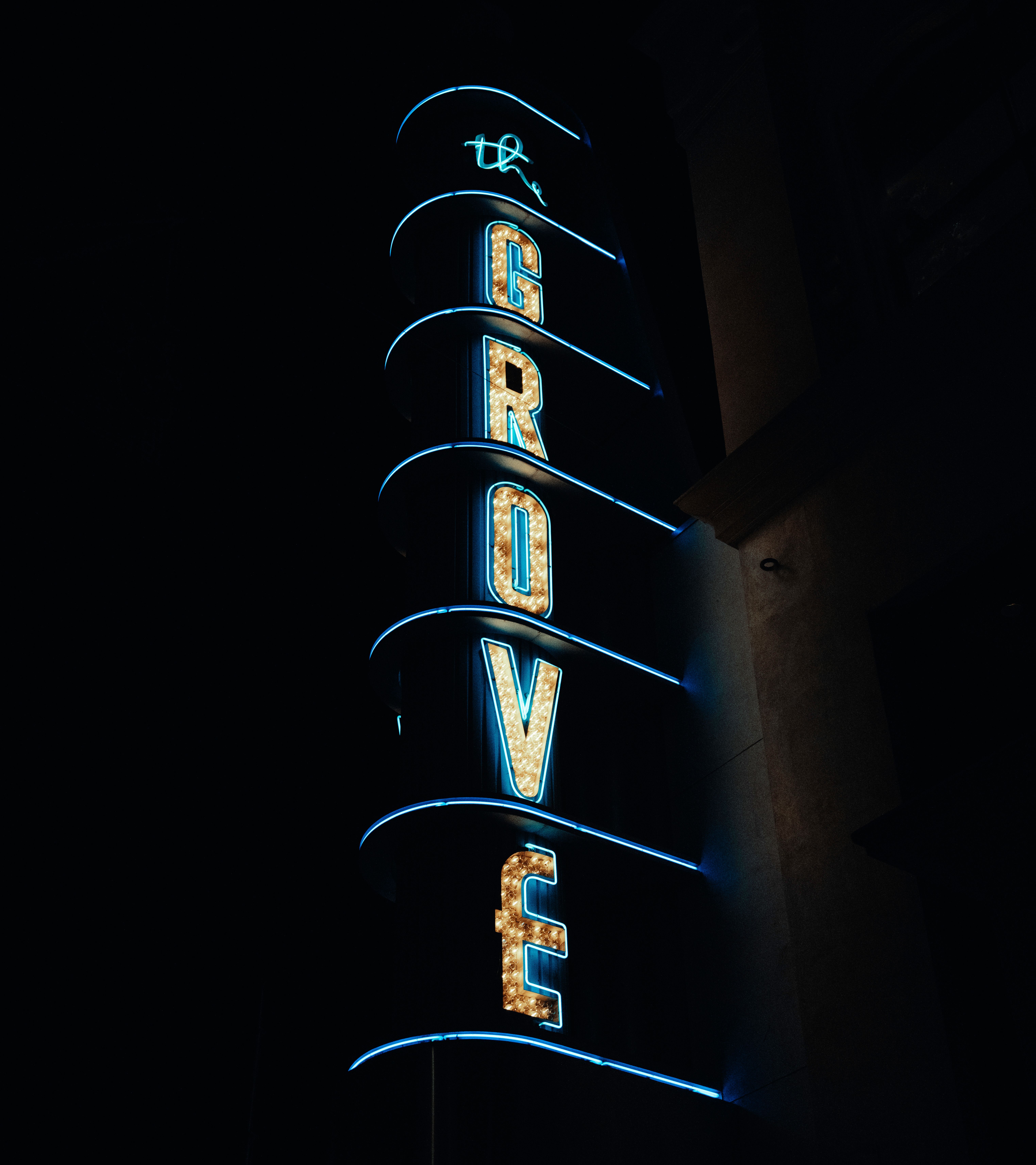 Vertical shot of The Grove's neon sign shining brightly in the night urban landscape.