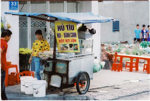 Colorful street food stall with vendors and customers in a lively Vietnamese street market.