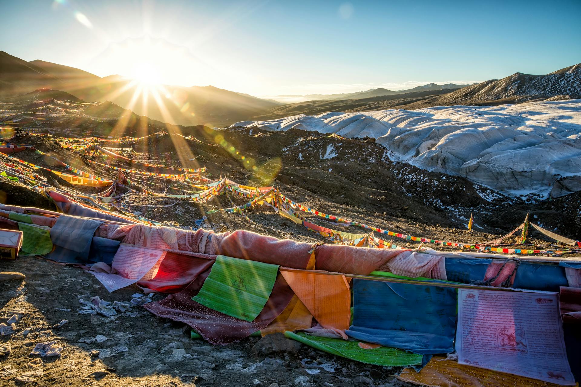 Vibrant Himalayan landscape with prayer flags at sunrise over snow-capped peaks.