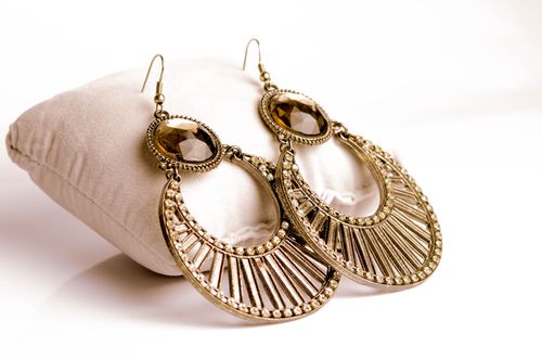 Free Close-up of intricately designed gold earrings resting on a plush white pillow for luxurious jewelry presentation. Stock Photo