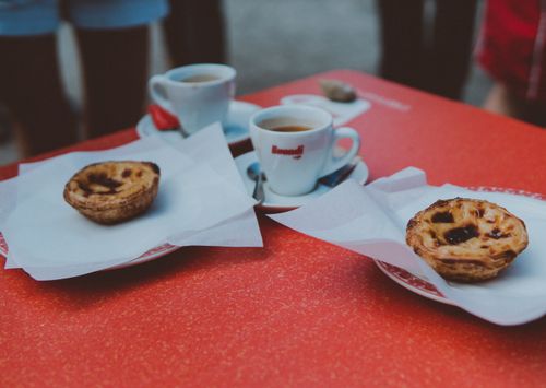 Free A delightful setup of pastel de nata pastries and coffee on a red outdoor table. Stock Photo