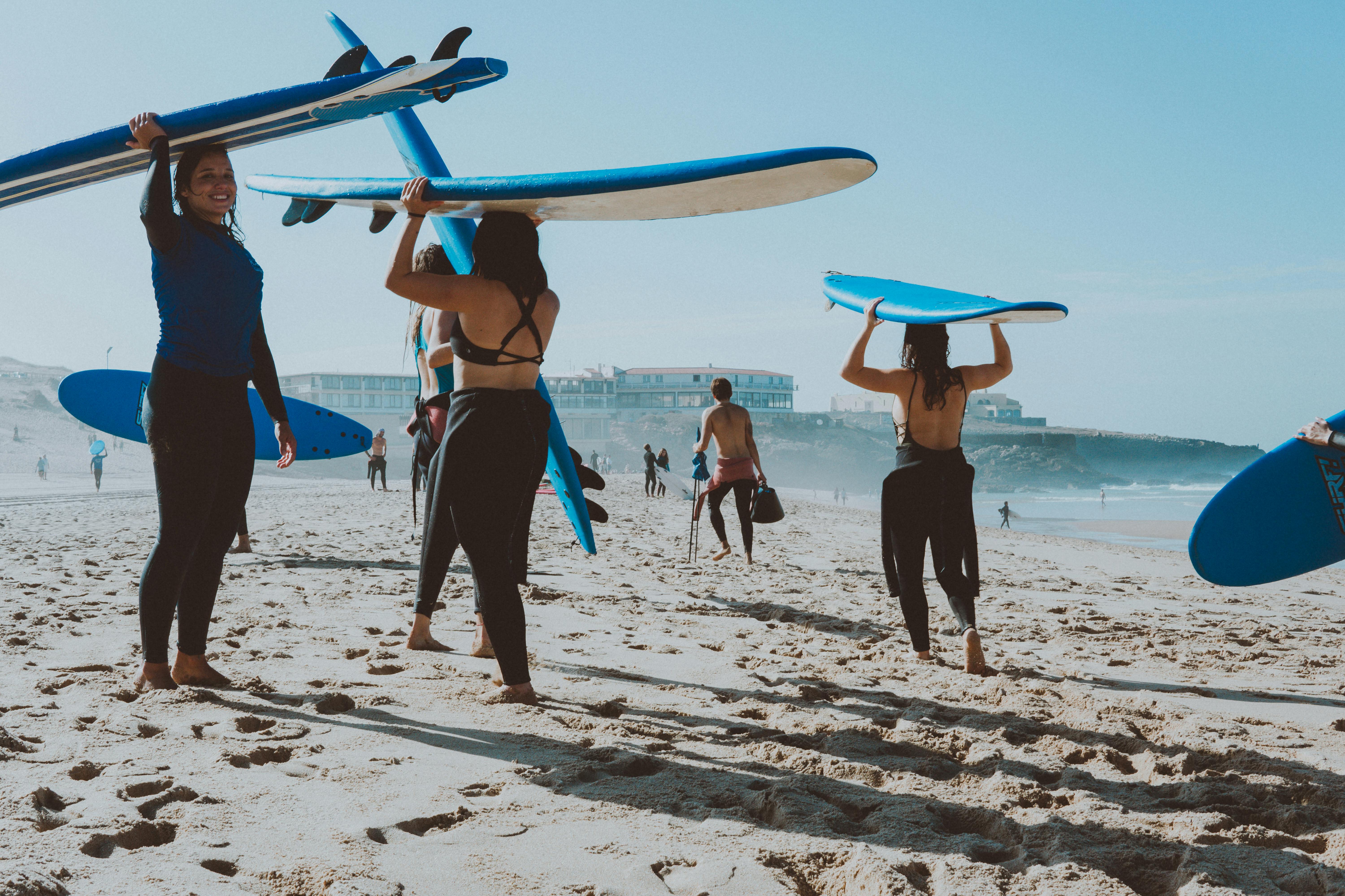 photo of people carrying surfboards